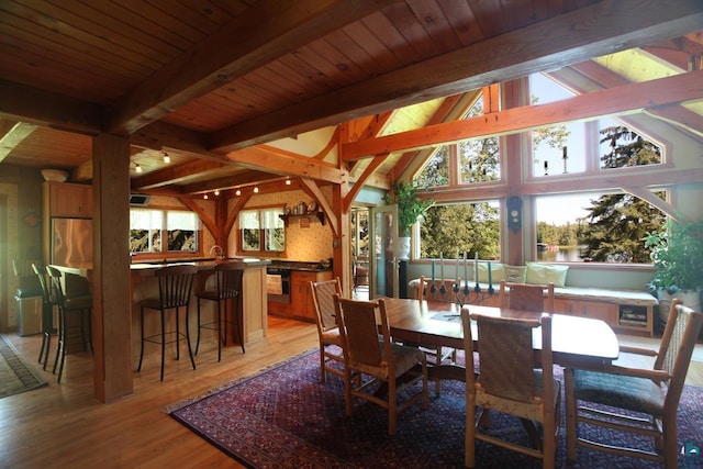 dining area featuring lofted ceiling with beams, wooden ceiling, light wood-style flooring, and a dry bar