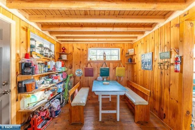 rec room featuring beamed ceiling, wooden walls, and wood-type flooring