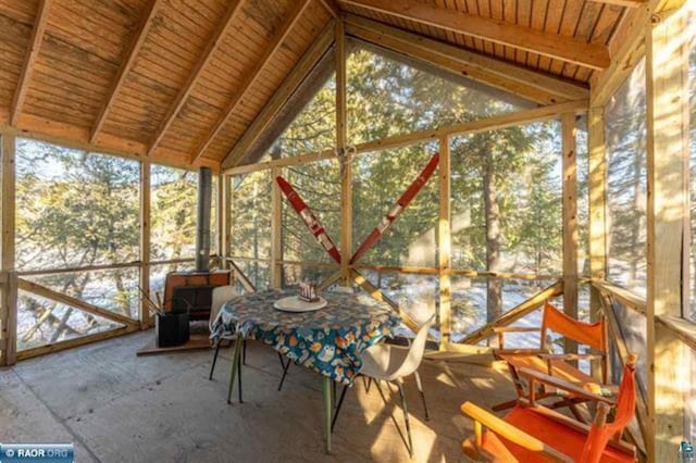 unfurnished sunroom featuring lofted ceiling with beams and a wood stove