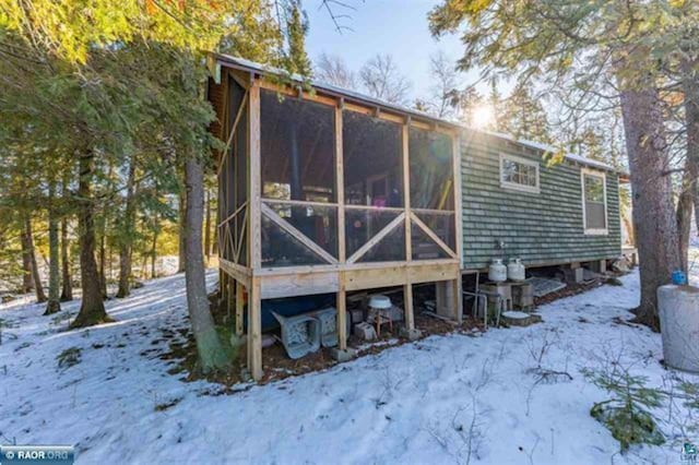 snow covered property featuring a sunroom