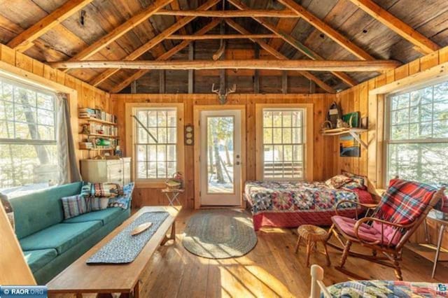 living room featuring plenty of natural light, wood ceiling, wood-type flooring, wooden walls, and lofted ceiling with beams