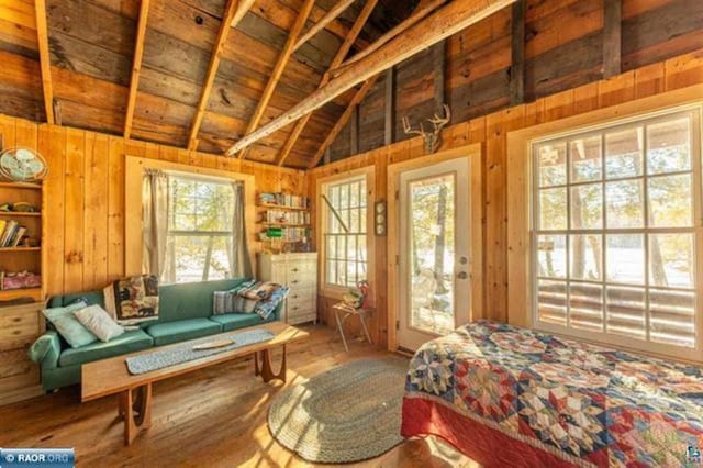 bedroom with multiple windows, vaulted ceiling with beams, and wood walls