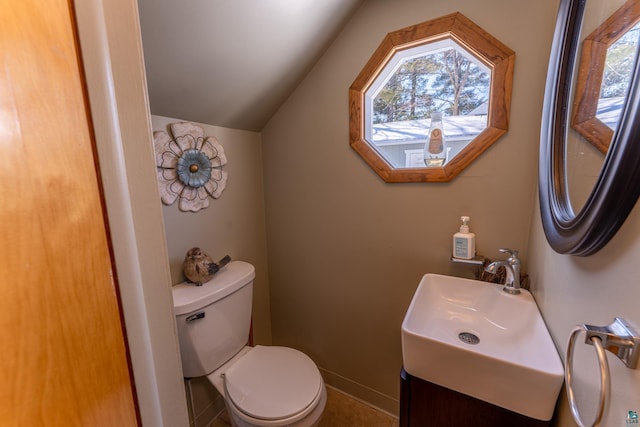 bathroom featuring lofted ceiling, toilet, and vanity