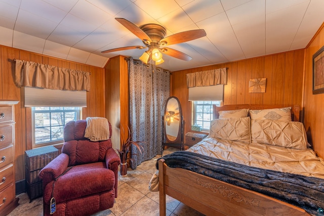 bedroom featuring ceiling fan, wooden walls, and multiple windows