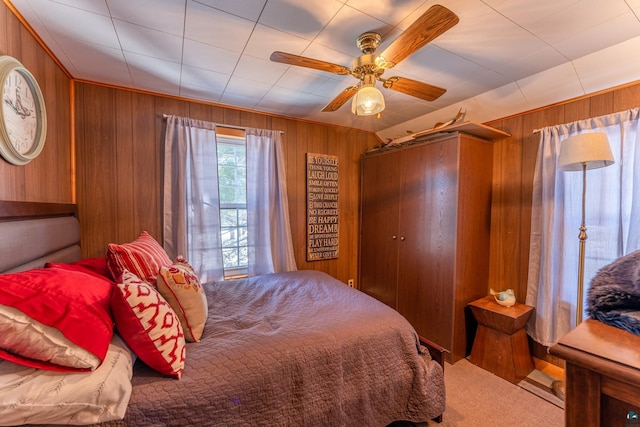 carpeted bedroom with wood walls and ceiling fan