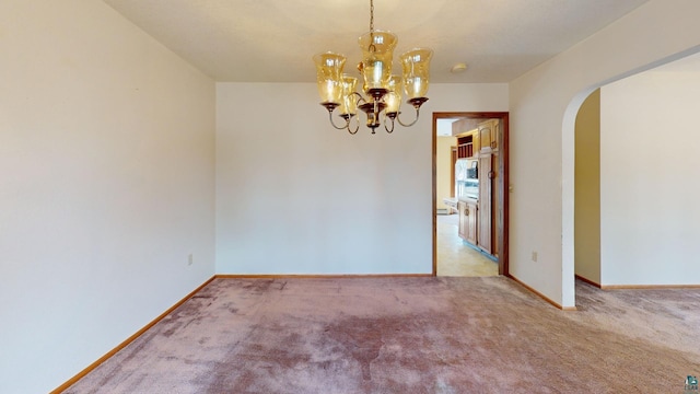 carpeted empty room featuring an inviting chandelier