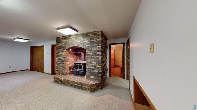 carpeted living room featuring a wood stove and brick wall