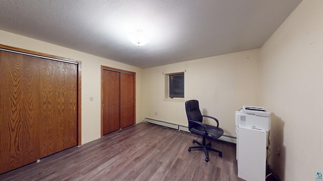 unfurnished office with a textured ceiling, a baseboard heating unit, and dark wood-type flooring