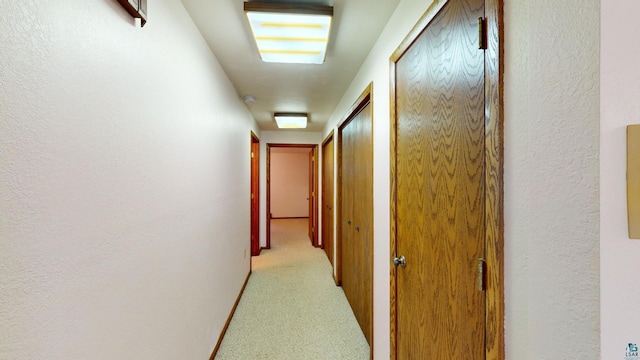 hallway featuring light colored carpet