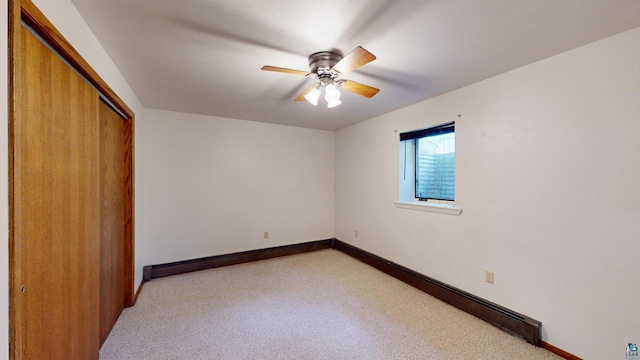 unfurnished bedroom with a closet, a baseboard radiator, ceiling fan, and light carpet