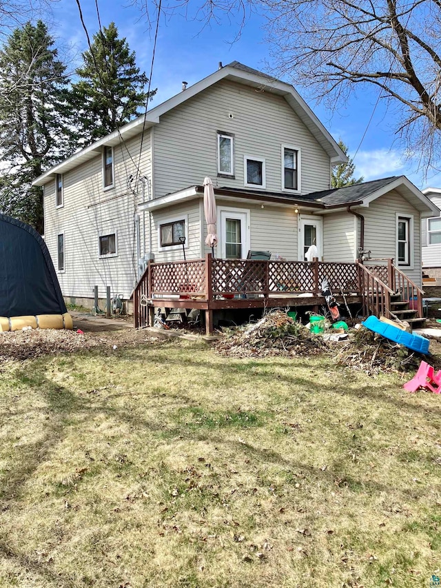 back of property with a deck and a yard