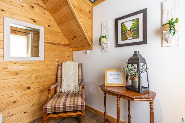 sitting room with wood-type flooring, wooden walls, and vaulted ceiling