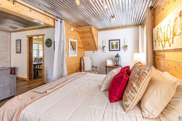 bedroom featuring wood walls, dark hardwood / wood-style flooring, ornamental molding, and brick wall