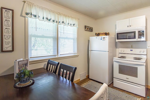 kitchen featuring white appliances, hardwood / wood-style flooring, white cabinetry, and ornamental molding