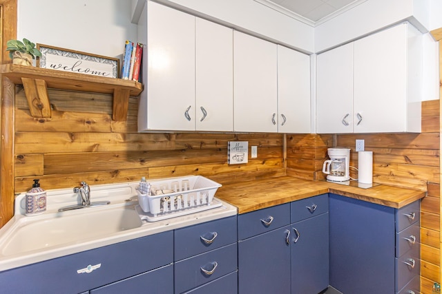 kitchen featuring wooden counters, crown molding, sink, blue cabinetry, and white cabinets