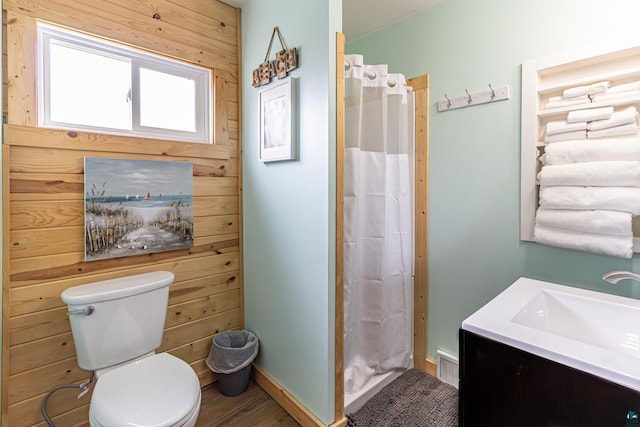 bathroom with wood walls, vanity, curtained shower, and toilet