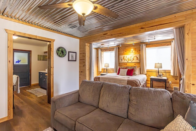 bedroom with multiple windows, ceiling fan, dark hardwood / wood-style flooring, and wood walls