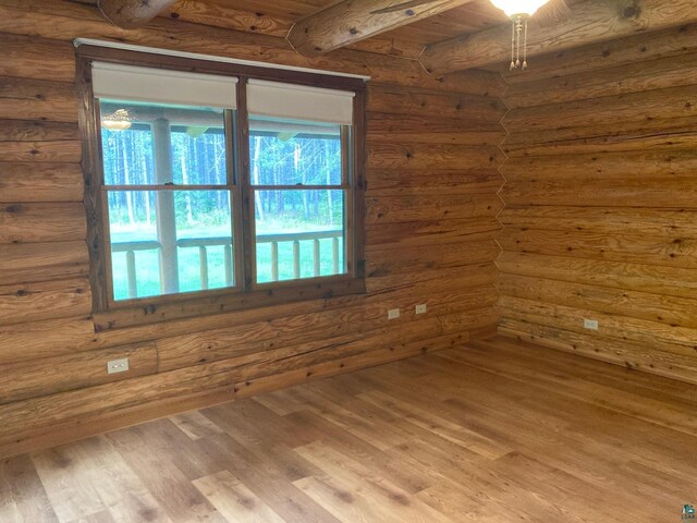 unfurnished room featuring beamed ceiling, hardwood / wood-style floors, wooden ceiling, and log walls