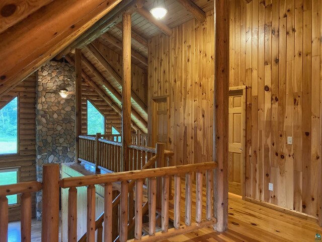 interior space featuring rustic walls, wood ceiling, wooden walls, hardwood / wood-style flooring, and vaulted ceiling with beams