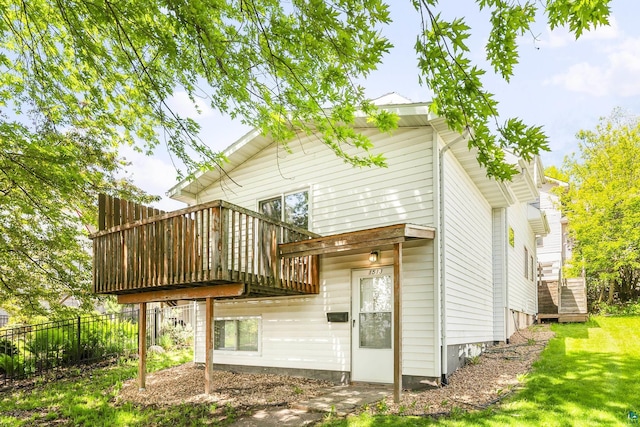 back of property with a deck and a lawn