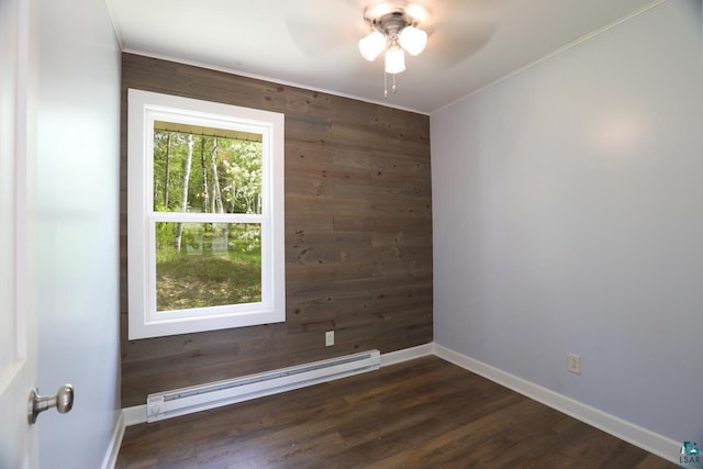 empty room with a baseboard heating unit, ceiling fan, dark hardwood / wood-style floors, and wooden walls