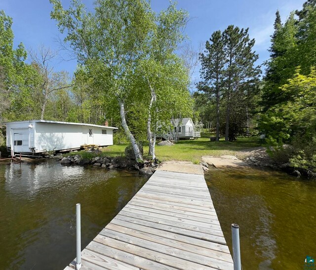 view of dock with a yard and a water view