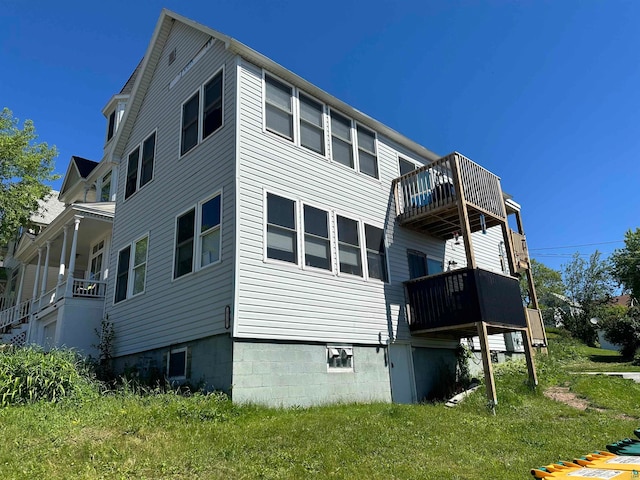 rear view of property featuring a lawn and a balcony