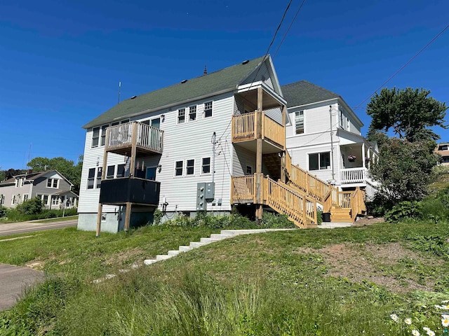 rear view of property with a balcony and a lawn