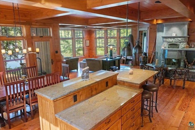 kitchen featuring light wood-type flooring, light stone countertops, a center island, and decorative light fixtures