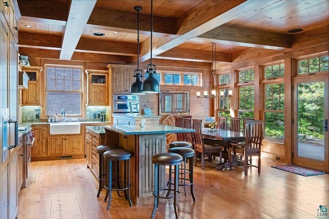 kitchen with oven, pendant lighting, a kitchen island, sink, and light hardwood / wood-style flooring