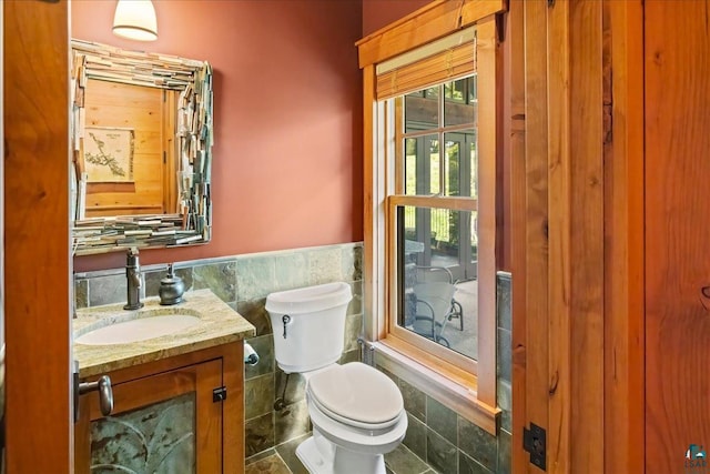 bathroom with toilet, tile walls, and vanity