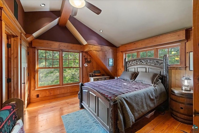 bedroom featuring ceiling fan, vaulted ceiling, wooden walls, and light hardwood / wood-style floors