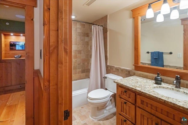 full bathroom featuring toilet, tile walls, vanity, and shower / bath combo with shower curtain