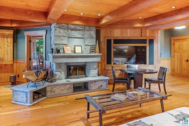 living area featuring beam ceiling, a fireplace, wood ceiling, and hardwood / wood-style flooring