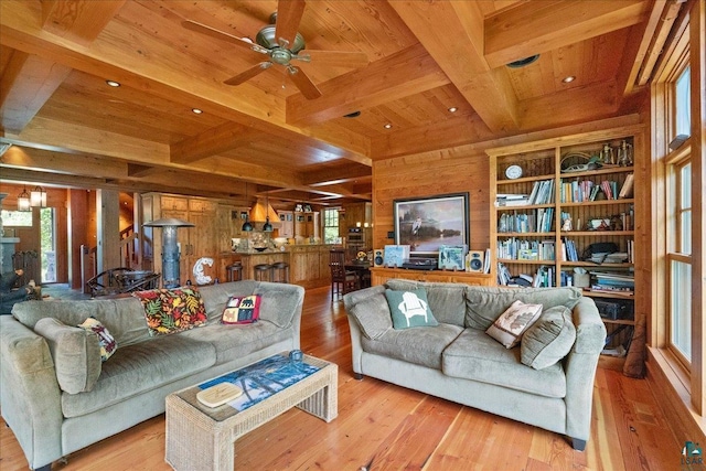 living room featuring a wealth of natural light, ceiling fan with notable chandelier, wood walls, and wooden ceiling