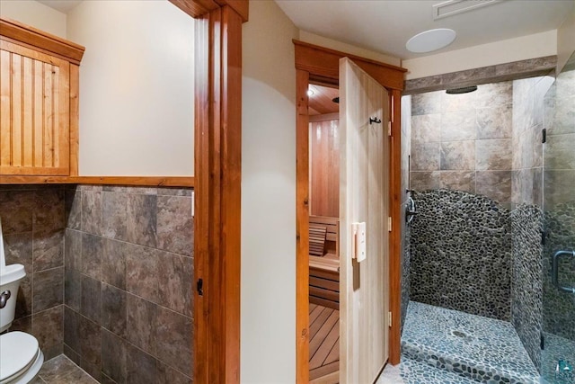 bathroom with tile walls, an enclosed shower, and toilet