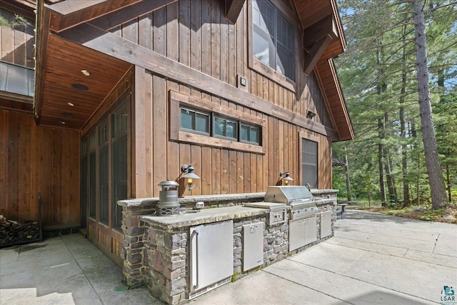 view of patio featuring exterior kitchen and a grill