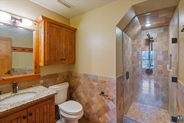 bathroom featuring an enclosed shower, vanity, tile walls, and toilet