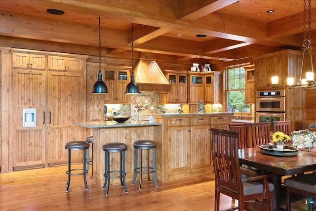 kitchen with pendant lighting, light hardwood / wood-style floors, decorative backsplash, beamed ceiling, and stainless steel double oven