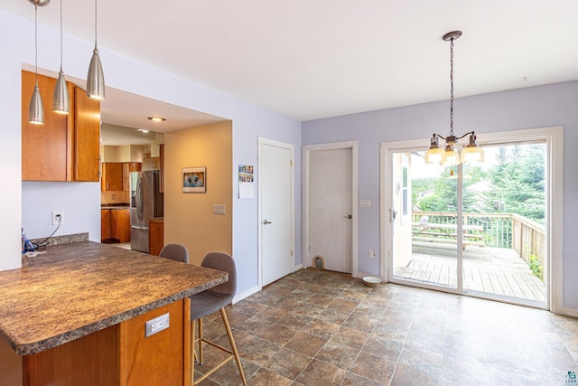 kitchen with a chandelier, stainless steel fridge, decorative light fixtures, and a breakfast bar area