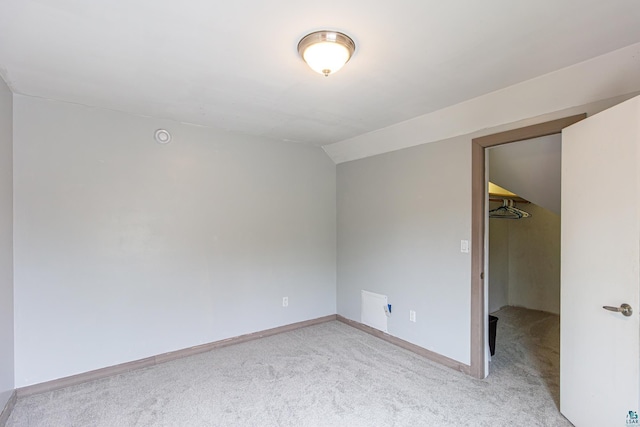 carpeted spare room featuring vaulted ceiling