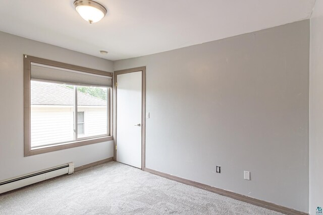 empty room featuring a baseboard radiator and light carpet