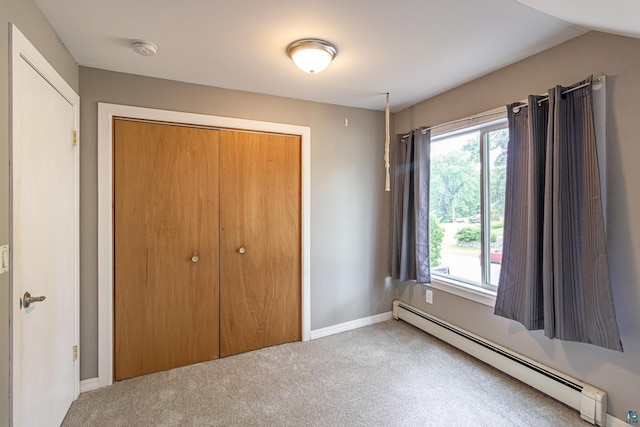 unfurnished bedroom featuring a baseboard radiator, carpet floors, and a closet