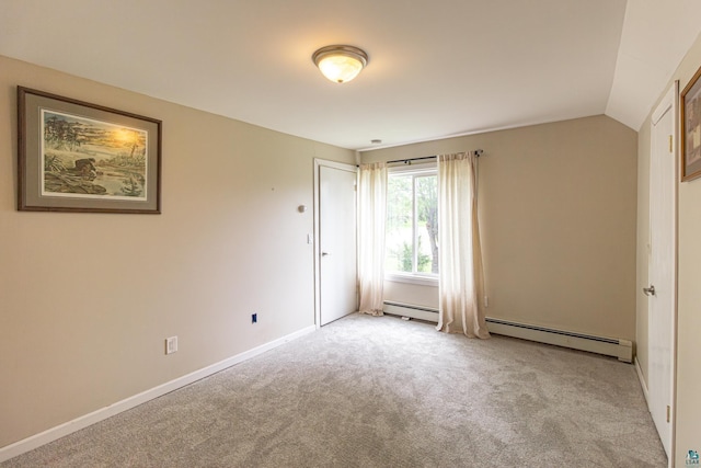 carpeted empty room featuring lofted ceiling and a baseboard heating unit