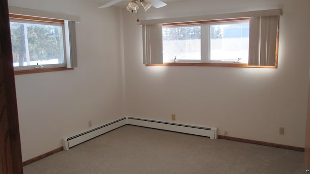 carpeted spare room with ceiling fan, a baseboard heating unit, and a wealth of natural light