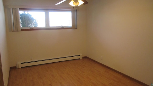 empty room featuring hardwood / wood-style flooring, ceiling fan, and a baseboard heating unit