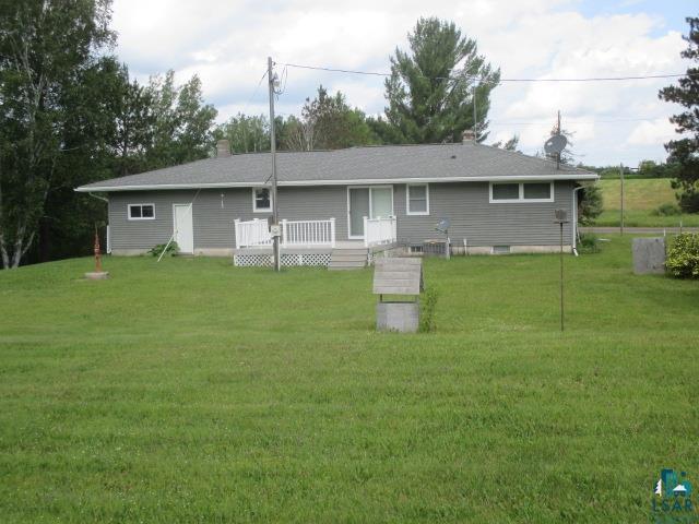 rear view of property featuring a yard and a wooden deck