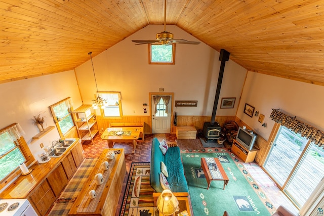 living room with a wood stove, ceiling fan, high vaulted ceiling, and wood ceiling