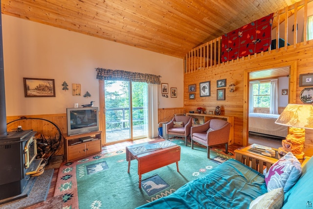 living room with a wood stove, wood walls, wood ceiling, and a high ceiling