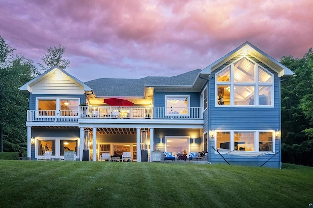 back of property with a shingled roof and a lawn